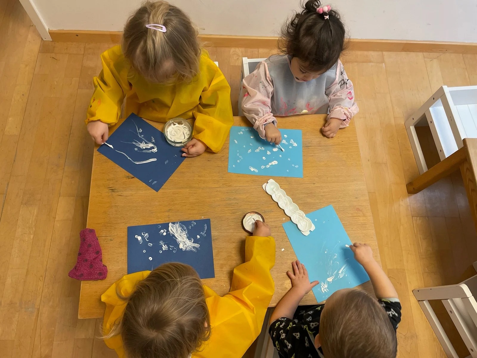Kinder basteln gemeinsam auf blauem Papier