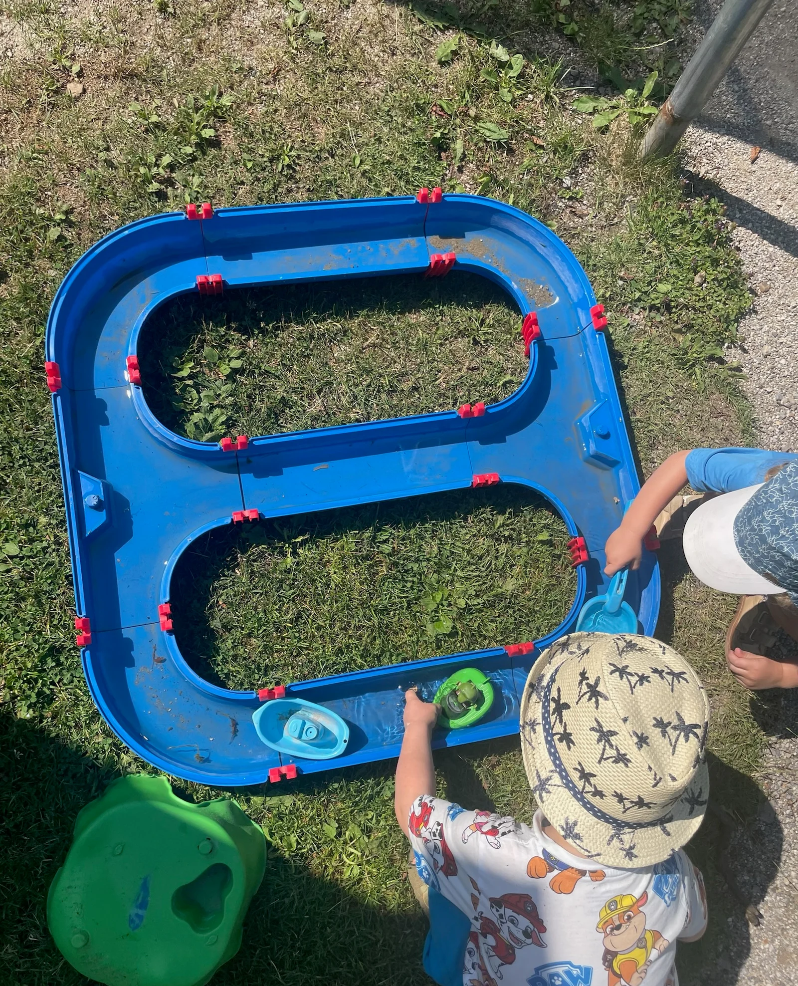Kinder spielen mit Booten an der Wasserbahn im Garten