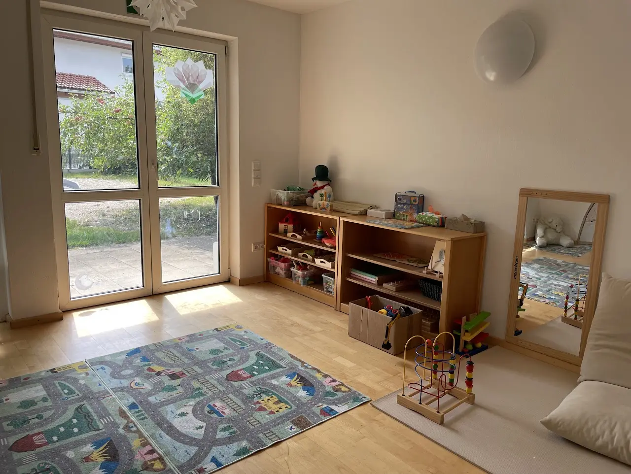 Heller Spielraum mit niedrigen Regalen und einem Kinderspiegel