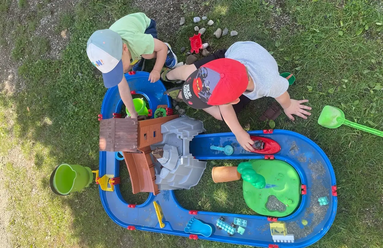 Kinder entdecken gemeinsam eine Wasser-Spielstation im Garten